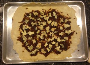 Blue cheese sprinkled evenly over the onion mixture, with enough dough around the border to fold over the edges of the filling, while pleating the edges as you go around, leaving the center open